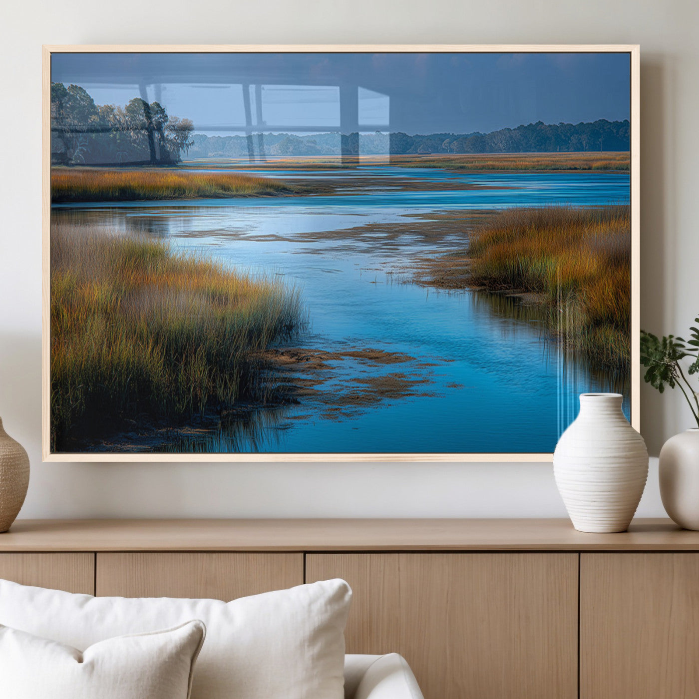 A peaceful marshland scene with calm blue water reflecting the surrounding grasses and trees, capturing the beauty of nature in a serene landscape.