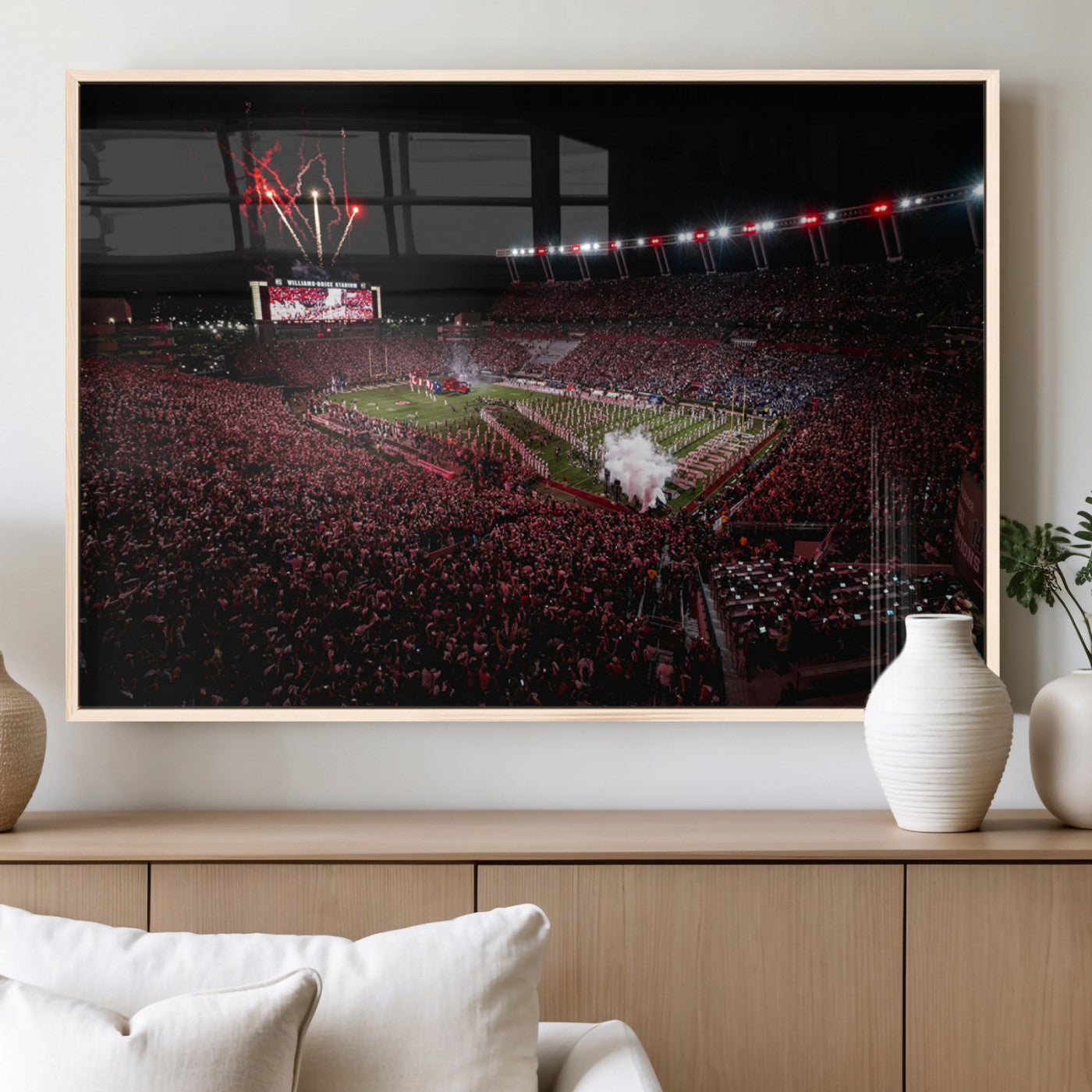 A dramatic shot of a packed stadium at night, with fireworks and smoke creating an exciting atmosphere for a live football game.