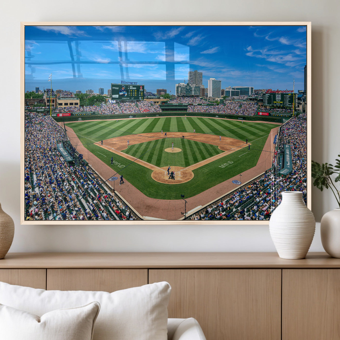 A wide-angle shot of a baseball field filled with spectators, with players on the field and the iconic Wrigley Field scoreboard in the background.