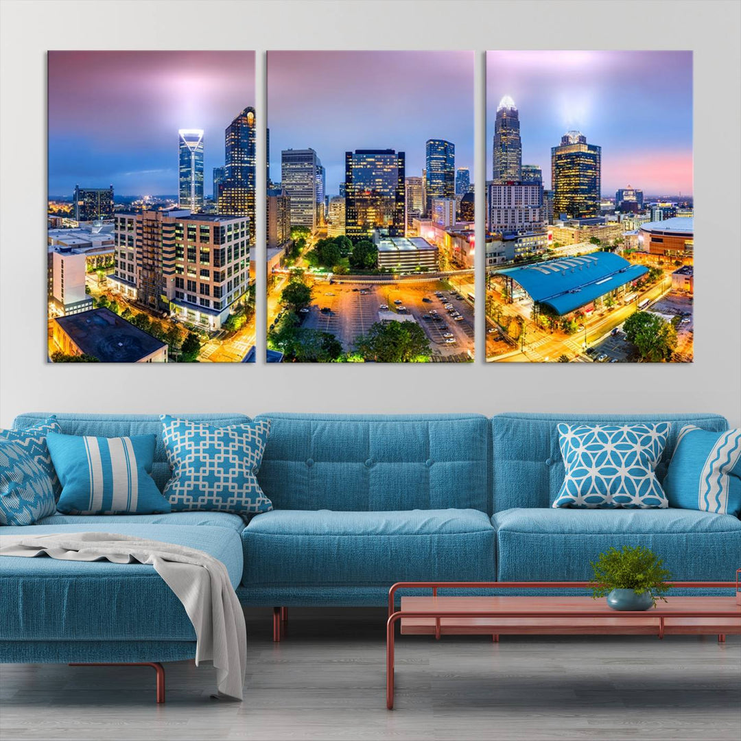 The living room features three large pieces of the *Charlotte City Lights Sunset Purple Skyline Cityscape View Wall Art Canvas Print*. Crafted on gallery-wrapped, museum-quality canvas with UV-protective coating, they grace the wall and add an artistic flair to the space.