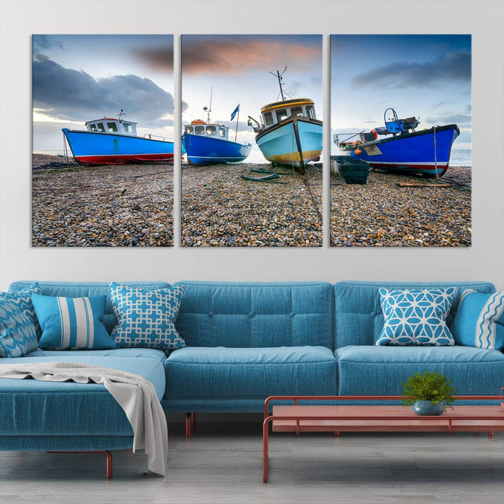 The "Big Boats On The Beach Wall Art Canvas Print" is a stunning piece featuring three museum-quality panels depicting fishing boats on a pebbled shore. Ready to hang and featuring UV-protective coating, it serves as an elegant addition to your home décor.