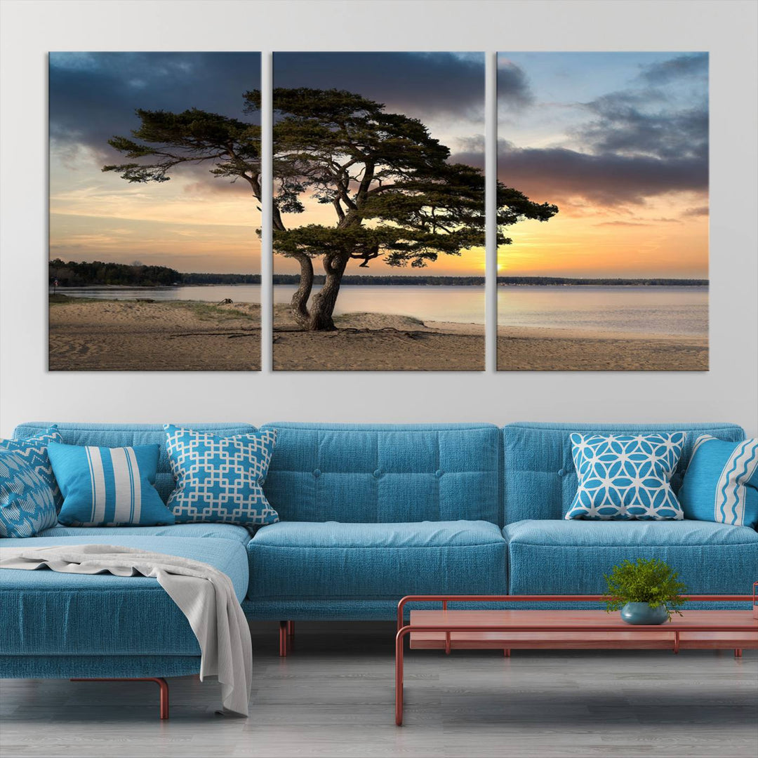 The room showcases the Coastal Sunset Wall Art Canvas Print, a triptych elegantly displayed on museum-quality polycotton canvas, depicting a serene beach sunset with a tree.