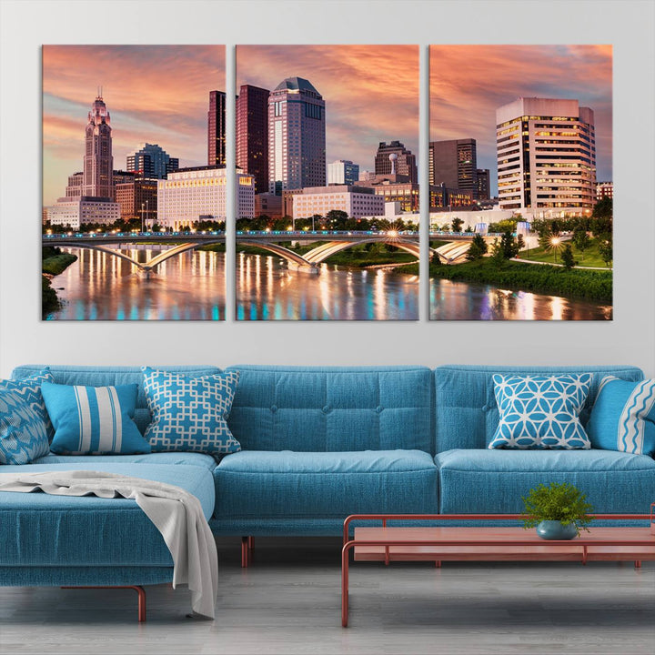 The "Columbus City Lights Sunset Orange Cloudy Skyline Cityscape View" wall art is featured on the wall. This triptych is printed on museum-quality canvas and includes a UV-protective coating, ensuring lasting vibrancy.