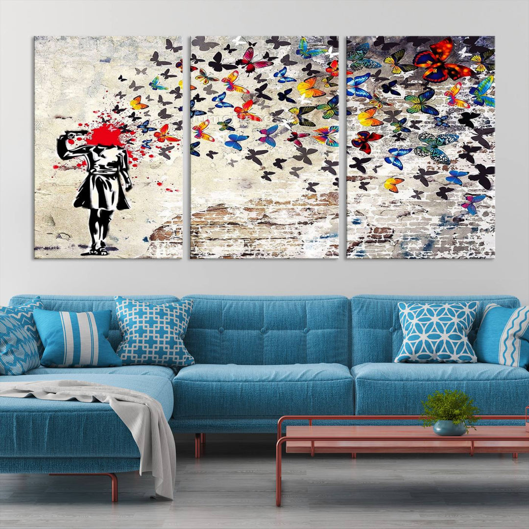 The Banksy Art Butterfly Girl Explosion Canvas showcases a dynamic figure with butterflies bursting from their head, set against a textured wall background. This vibrant urban graffiti piece is perfect for modern interiors and comes ready to hang.