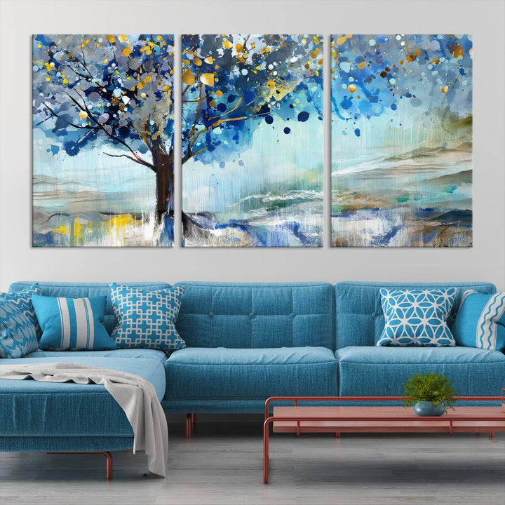 A modern living room features a three-panel Watercolor Style Abstract Tree Printing Wall Art Canvas in vibrant blue and yellow, crafted on museum-quality material.