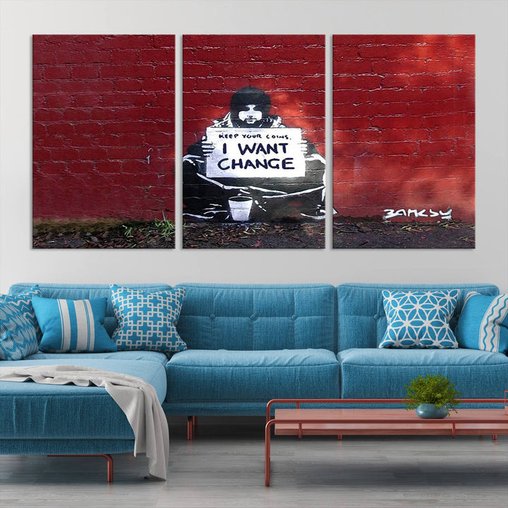 The living room showcases a triptych of stencil artwork on museum-quality canvas, featuring the Banksy I Want Change Graffiti Abstract Wall Art Canvas Print. This captivating piece depicts a person holding a sign that says "I want change" and is finished with a UV-protective coating to ensure long-lasting beauty.