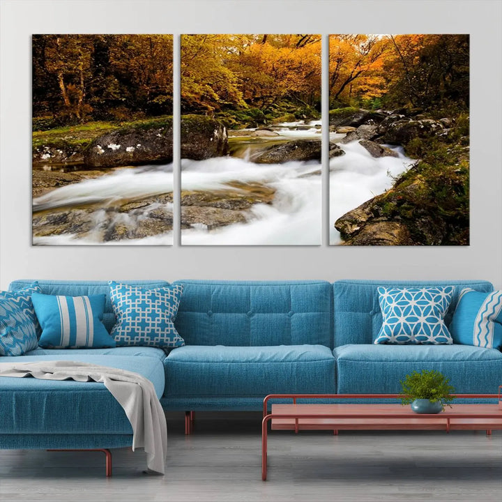 The living room is adorned with the "Wall Art Waterfall Canvas Print River in Forest in Autumn," a triptych on museum-quality canvas showcasing a flowing river surrounded by autumn trees. This ready-to-hang artwork features a UV-protective coating to ensure enduring vibrancy.