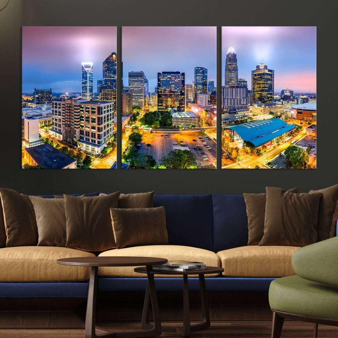 The living room features three large pieces of the *Charlotte City Lights Sunset Purple Skyline Cityscape View Wall Art Canvas Print*. Crafted on gallery-wrapped, museum-quality canvas with UV-protective coating, they grace the wall and add an artistic flair to the space.