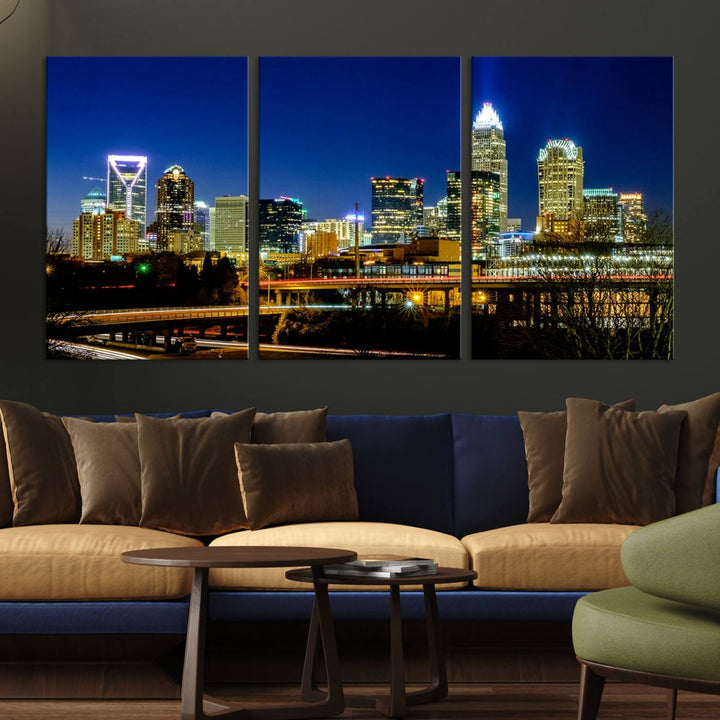 The Charlotte City Lights Night Blue Skyline Cityscape View Wall Art Canvas Print, showcasing an illuminated city skyline at night, is printed on museum-quality canvas with a UV-protective coating. Enhance your space with this stunning piece and enjoy free shipping with your purchase.