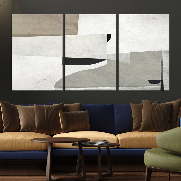 The Brown Gray Figures Abstract Wall Art Canvas Print is displayed as a triptych on a dark wall. The piece is gallery wrapped, offering a seamless finish and enhanced durability due to its UV-protective coating.