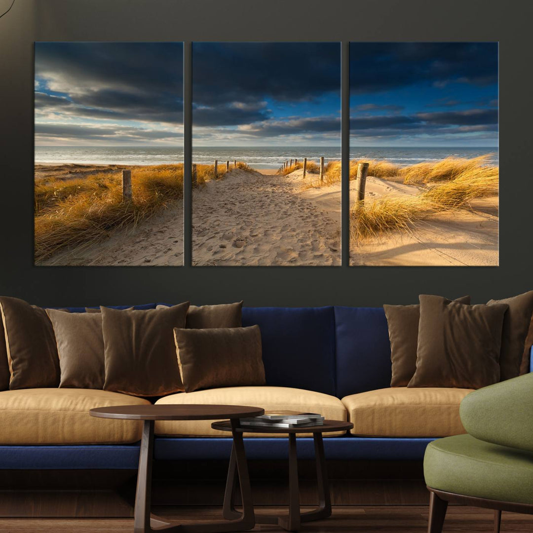 The Ocean Beach Dark Clouds Wall Art Canvas Print is a breathtaking triptych depicting a sandy beach path with tall grasses under an intense cloudy sky. It is crafted on museum-quality canvas with UV protection.