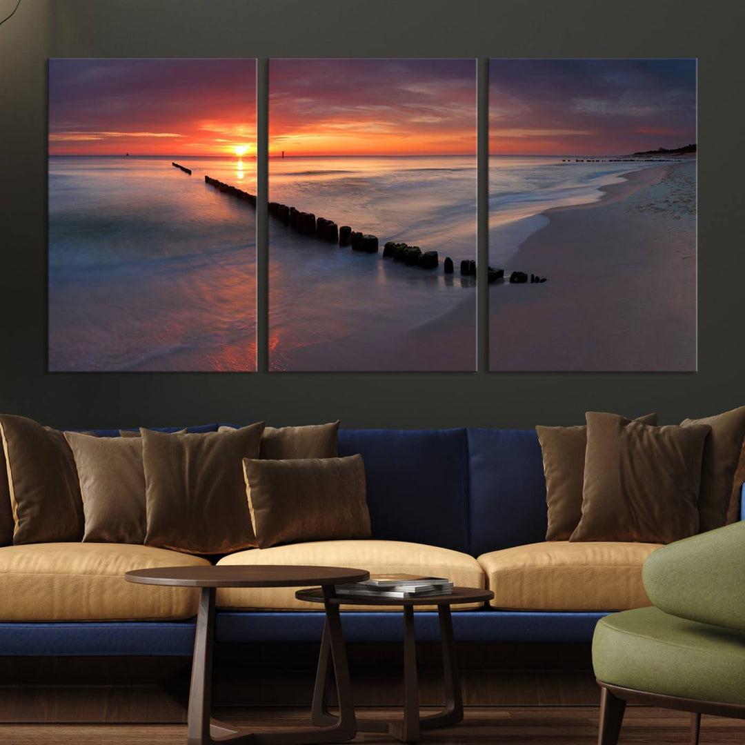 In a modern living room, the Sunset Beach Wall Art Canvas Print is displayed above. This triptych, printed on museum-quality canvas with a UV-protective coating, ensures lasting brilliance. It's ready to hang and brings an elegant touch to your space.