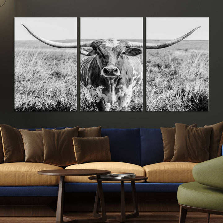 The Texas Cow Longhorn Wall Art Canvas Print is a black and white triptych depicting a cow in a field. It is crafted with museum-quality canvas and features a UV-protective coating.