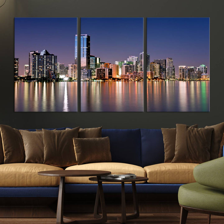 The Miami Skyline Canvas Wall Art Print showcases a vibrant night cityscape and beautifully captures the dazzling colorful lights reflecting on the water. This ready-to-hang triptych adorns the wall, creating a stunning visual centerpiece.