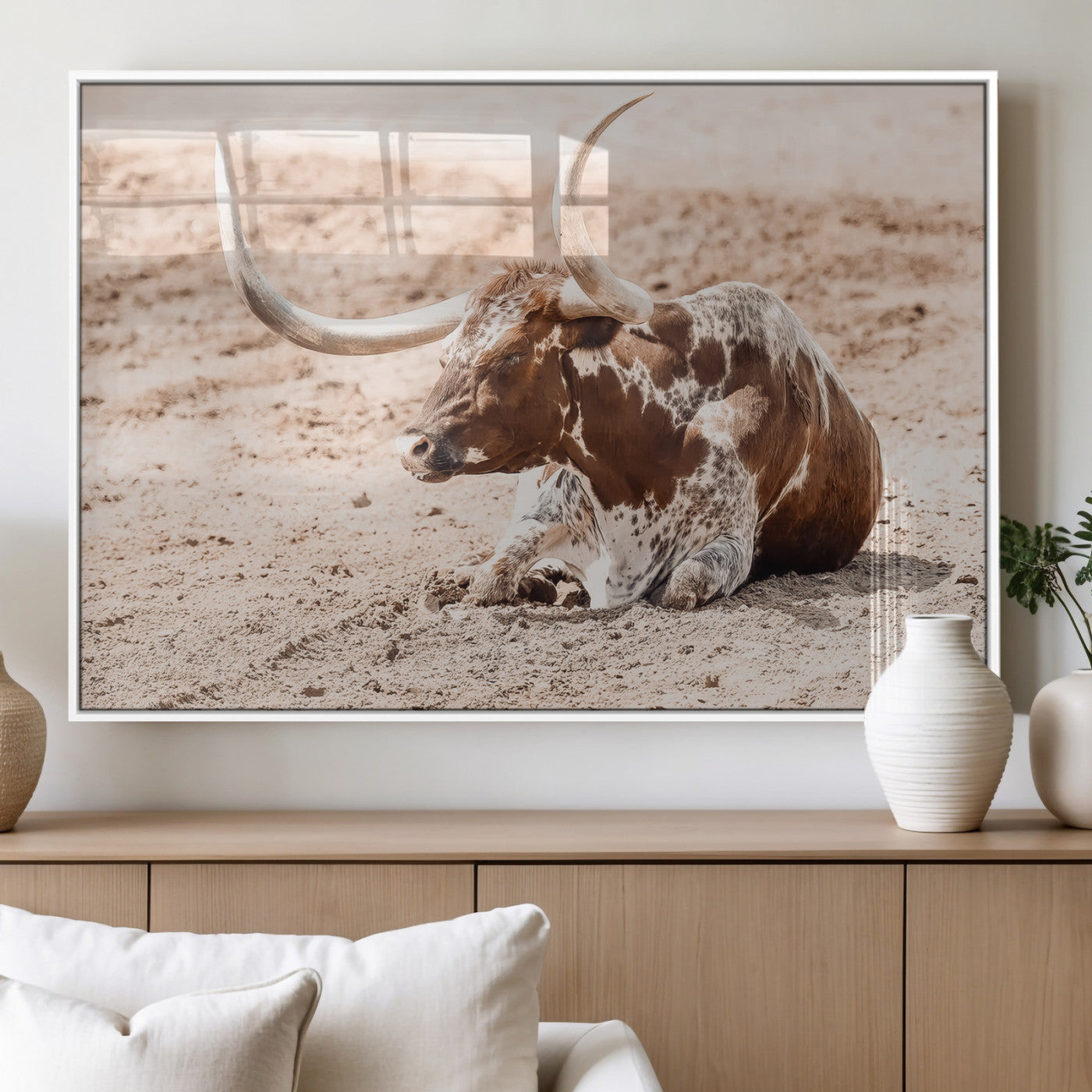 Texas Longhorn bull resting on dusty ground with warm tones, ideal for rustic western or farmhouse-themed wall decor.