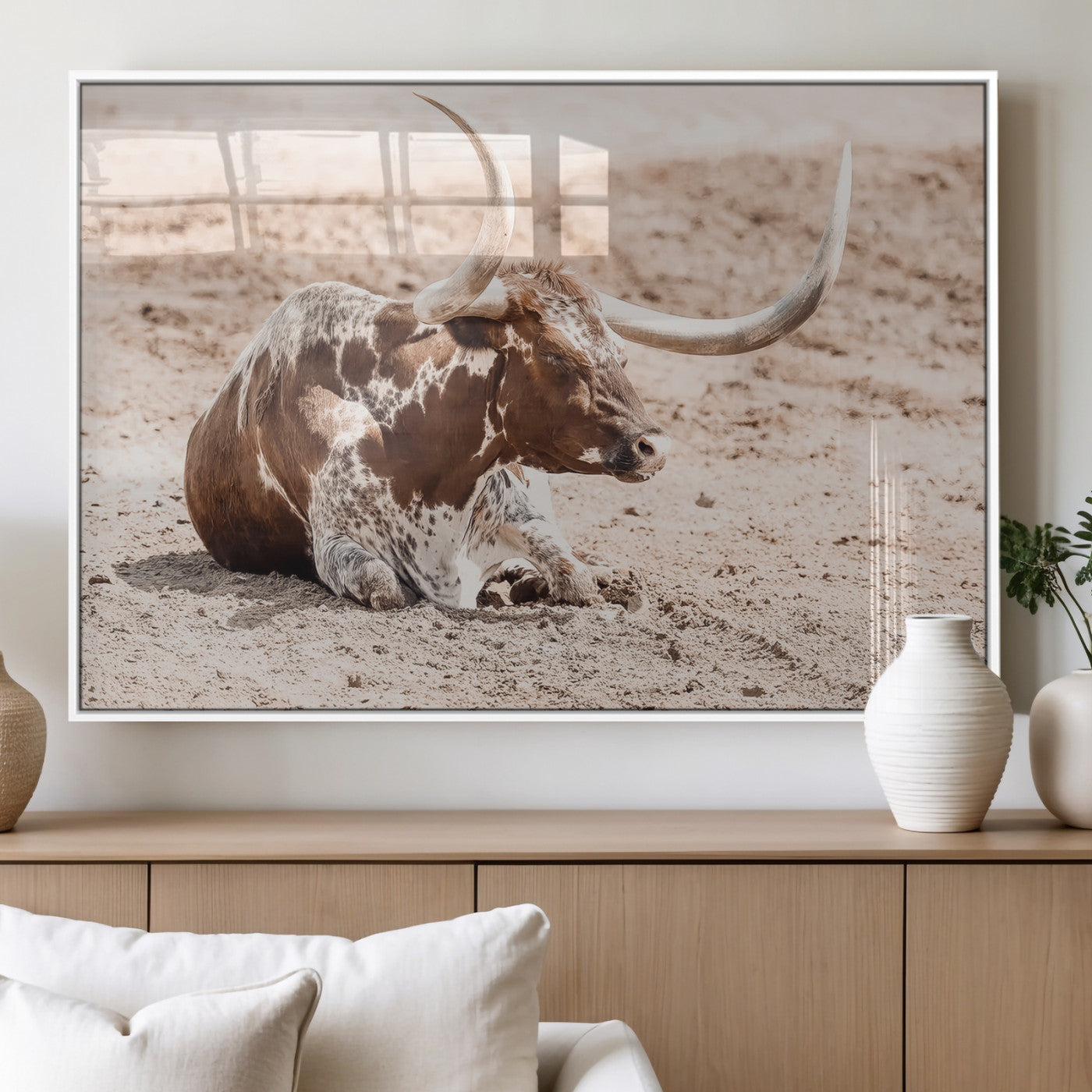 Texas Longhorn bull resting on dusty ground with warm tones, ideal for rustic western or farmhouse-themed wall decor.