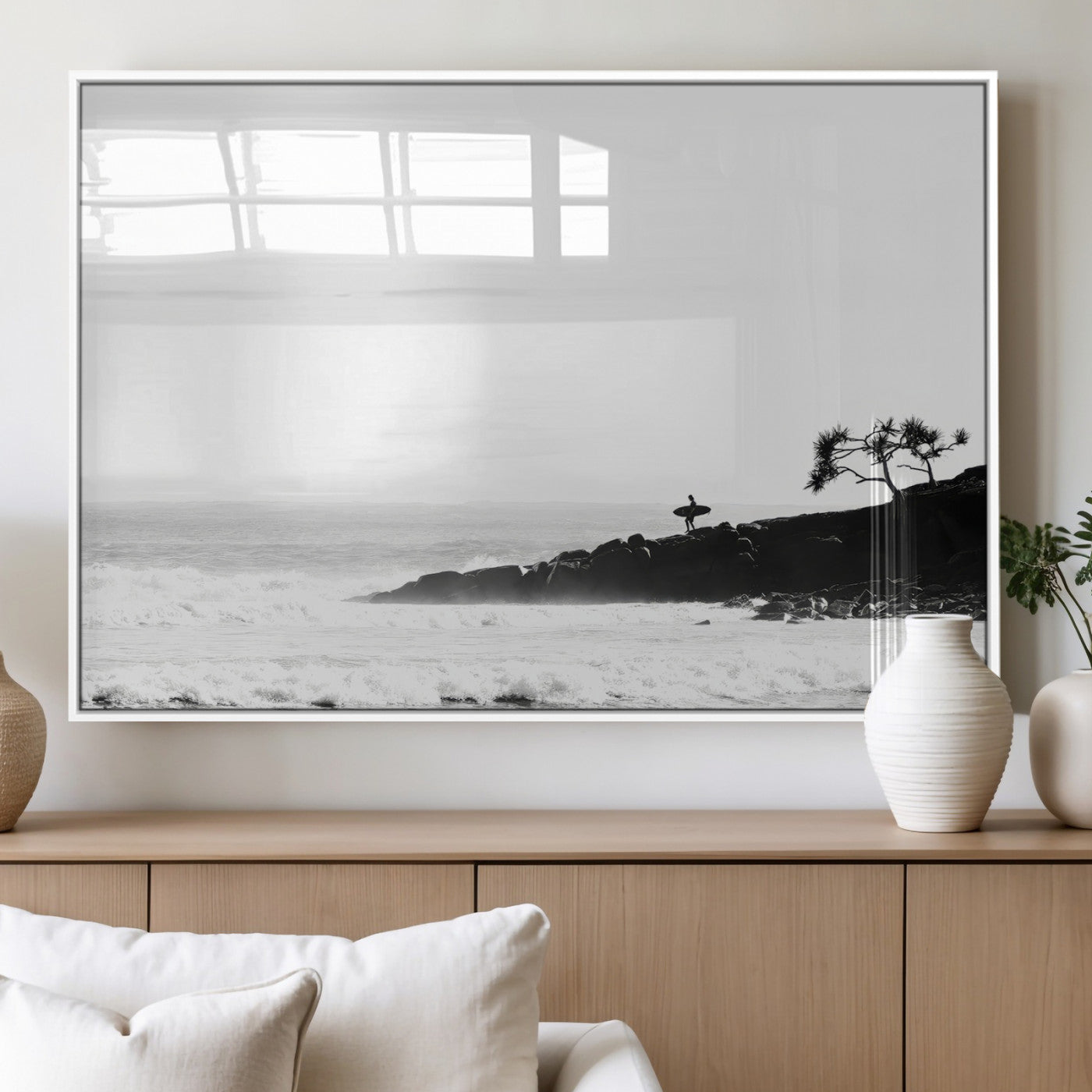 Black and white photo of a surfer standing on rocky cliffs, gazing at the waves, embodying the spirit of adventure and solitude.
