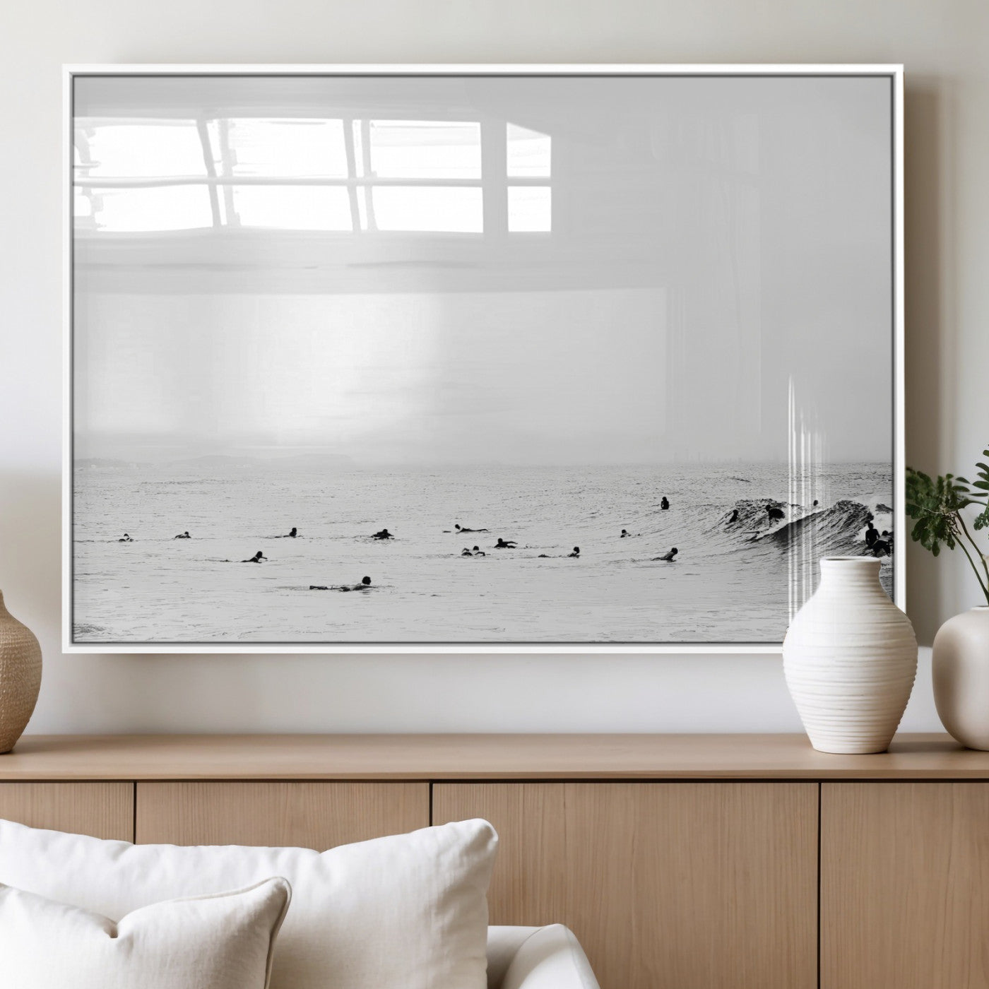 A group of surfers floating in the ocean, waiting for waves under a vast, moody sky, captured in black and white.