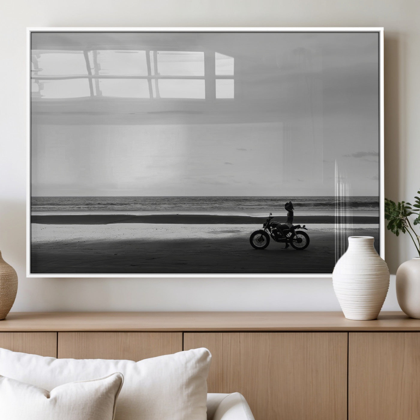 A motorcyclist on a vast beach, gazing at the ocean, capturing a moody and tranquil coastal adventure in black and white.