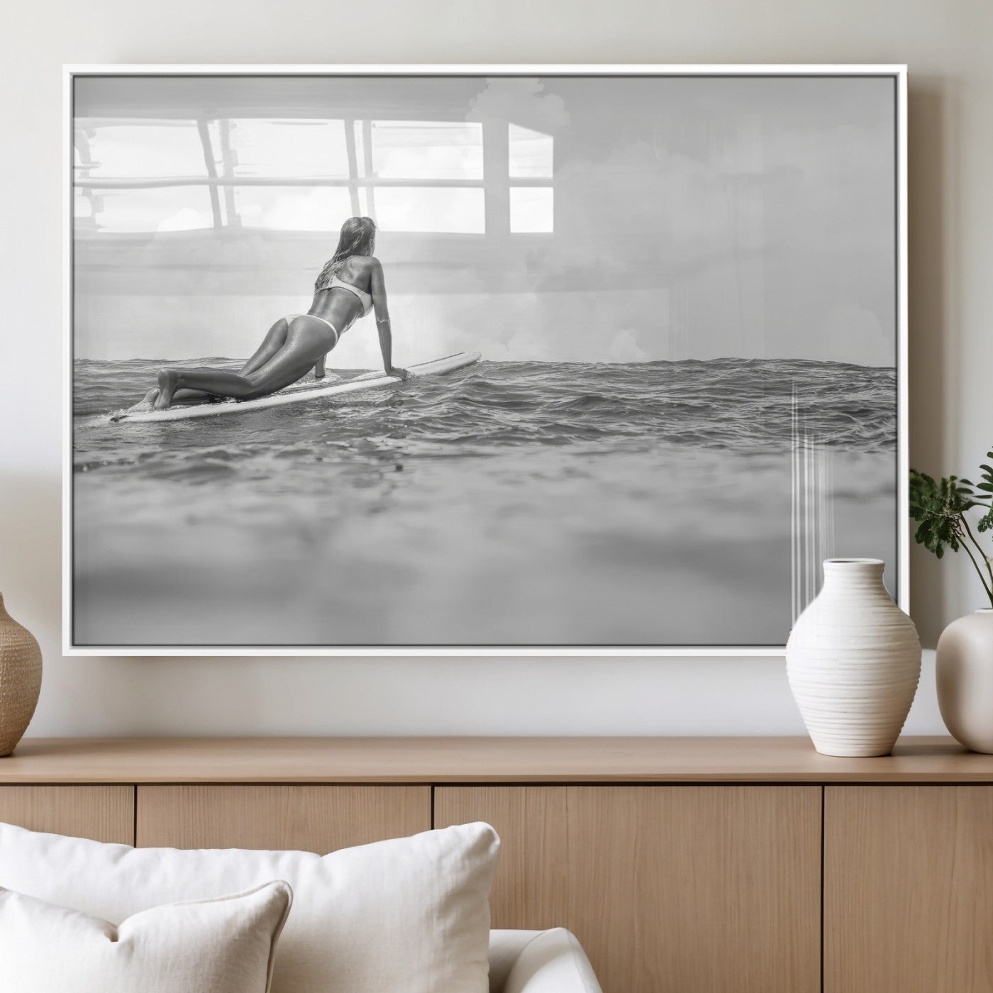A black and white ocean scene featuring a surfer girl waiting on her board, gazing at the horizon, capturing a tranquil and adventurous coastal moment.