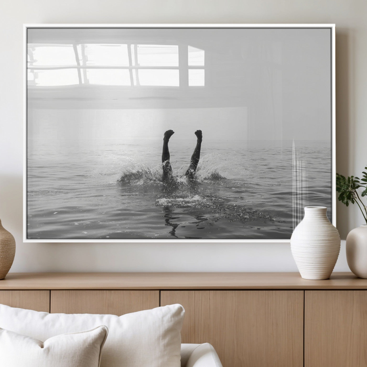 A black and white minimalist water scene capturing a playful splash as a swimmer dives upside down, creating a carefree and artistic aquatic aesthetic.