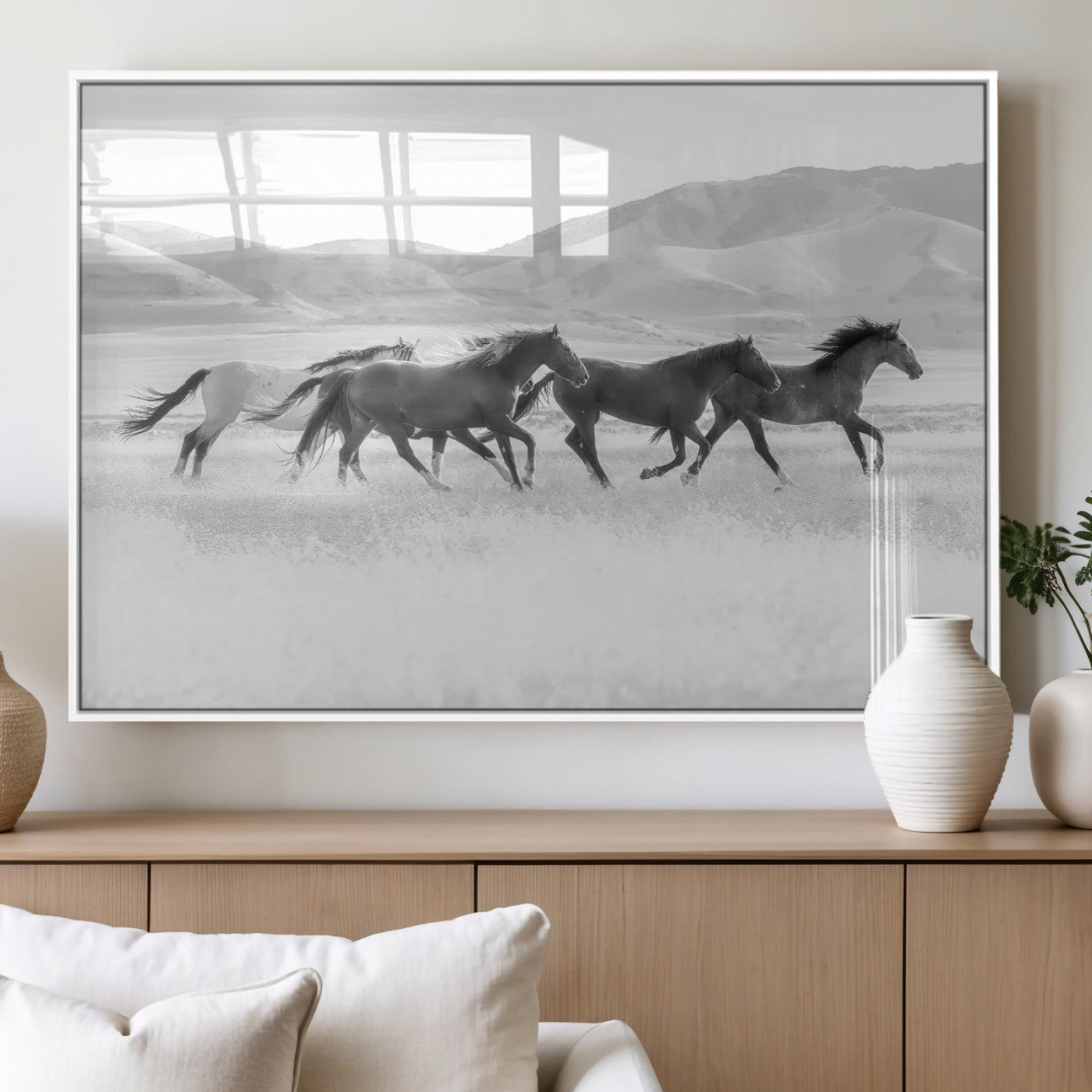A black and white image of wild horses running freely across an open grassland, capturing the power and beauty of untamed nature in a rustic western setting.