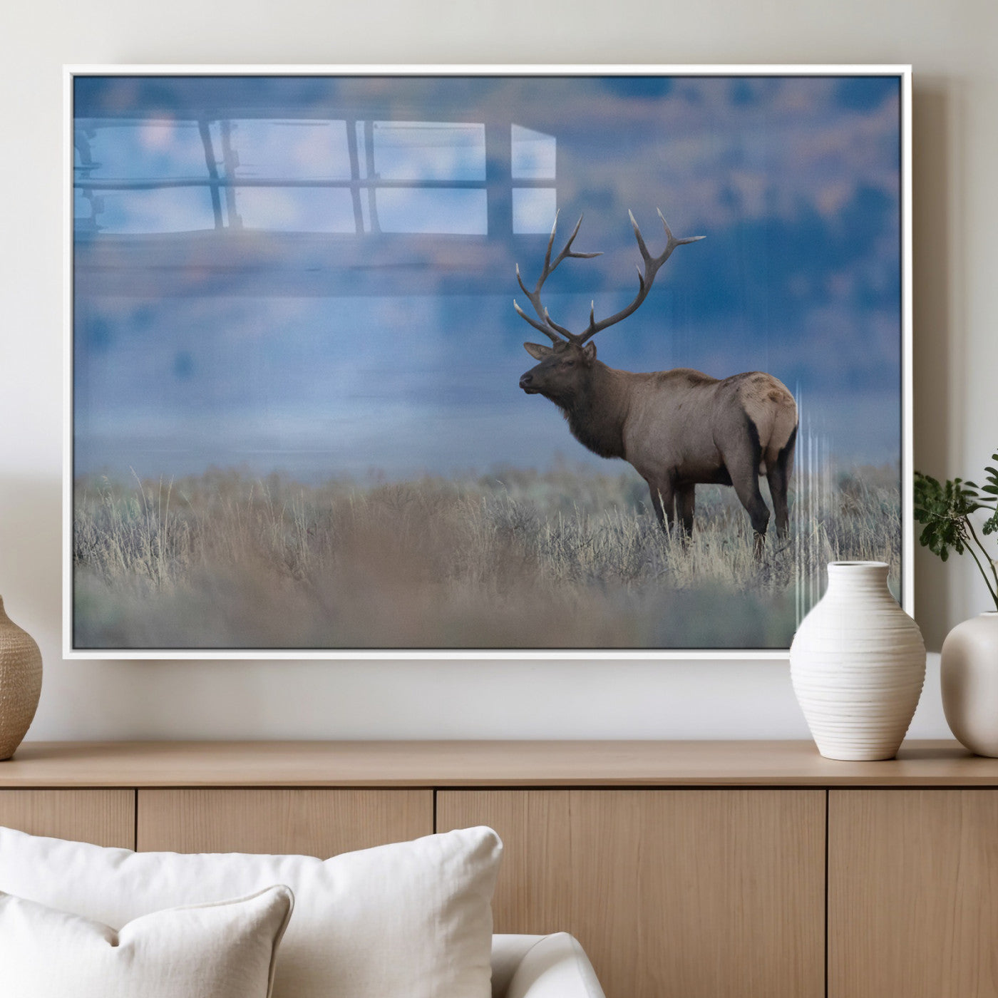 Elk with large antlers standing in open field, mountains blurred in background, perfect for rustic cabin or lodge-style decor.