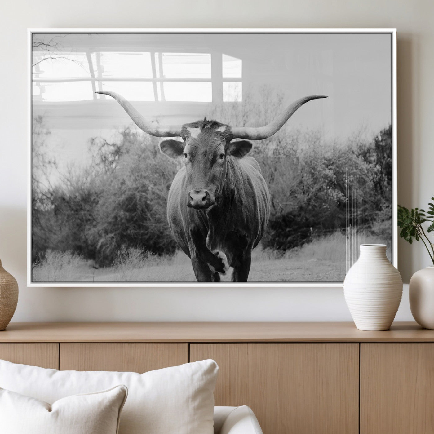Black and white photo of a longhorn cow in a field, perfect for rustic farmhouse or western-themed interior wall decoration.