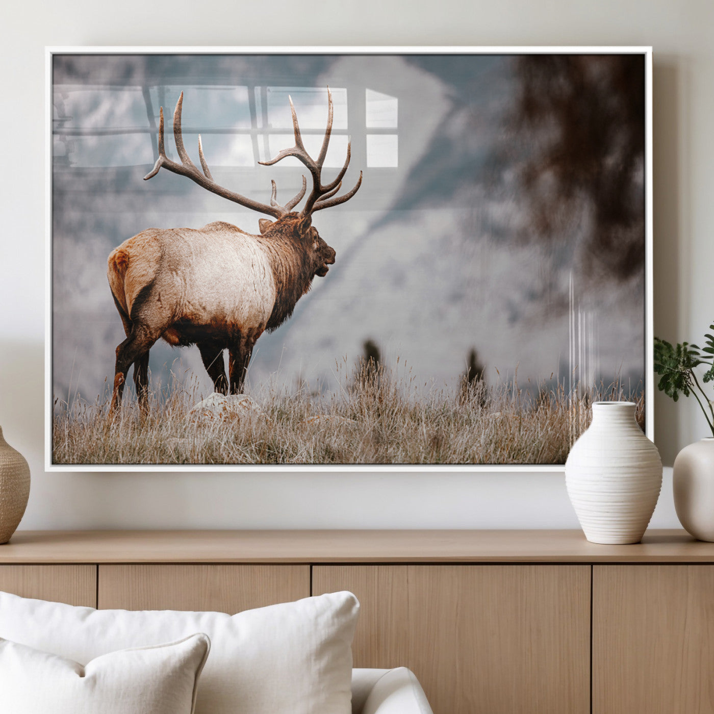 Majestic elk with large antlers standing in grass with snowy mountains in background, perfect for rustic cabin or lodge style decor.