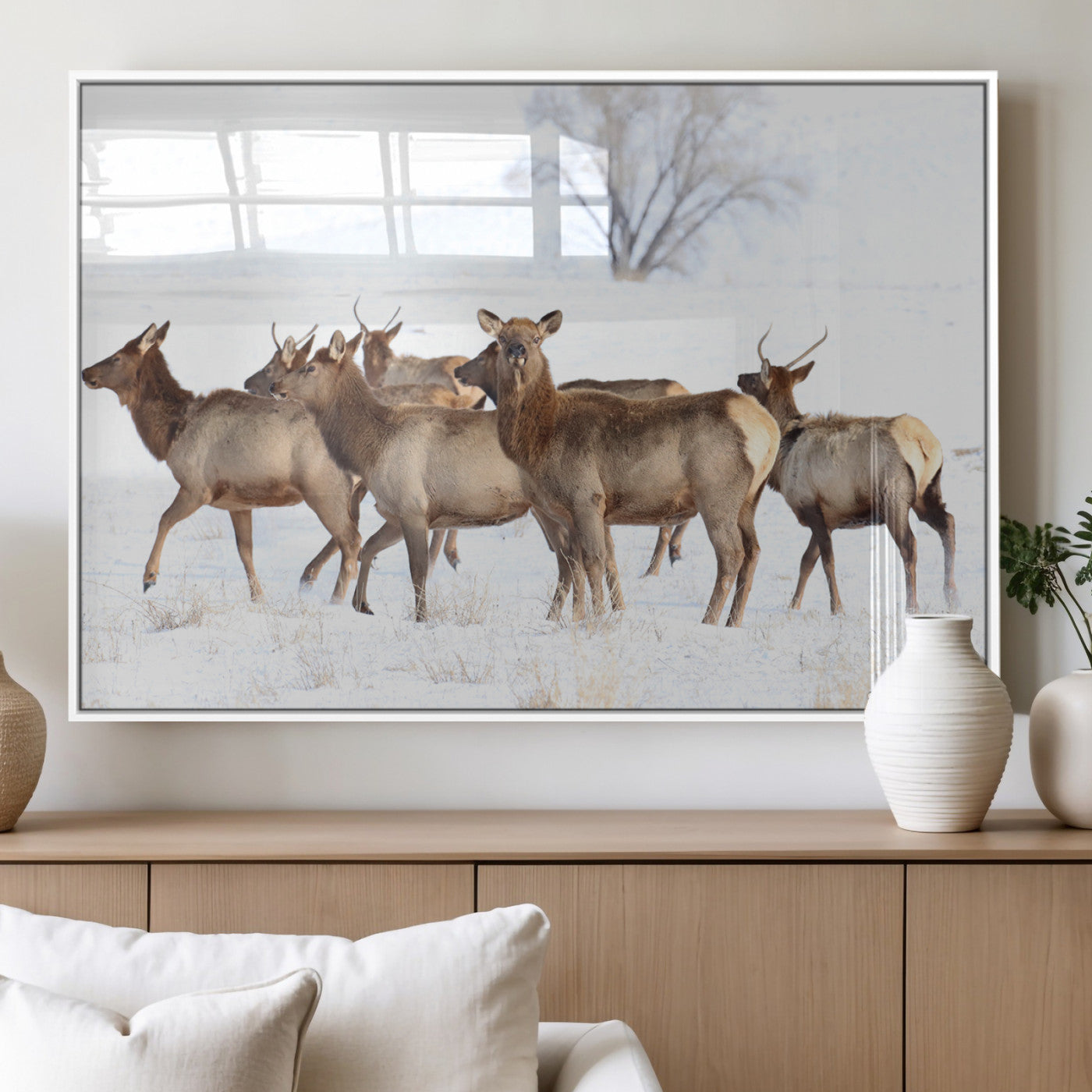 A group of elk standing on snowy terrain with a tree in the background, perfect for rustic or lodge-style winter wall decor.