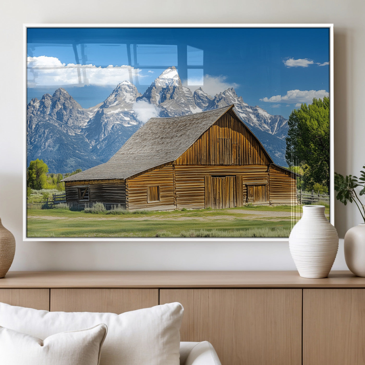 A rustic wooden barn sits in front of towering mountain peaks under a clear blue sky, perfect for farmhouse or cabin style interiors.