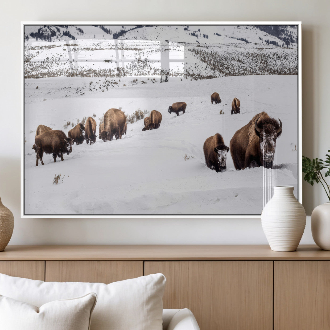 A herd of bison walking through deep snow in a mountain valley, perfect for rustic, cabin or western-themed wall decor.