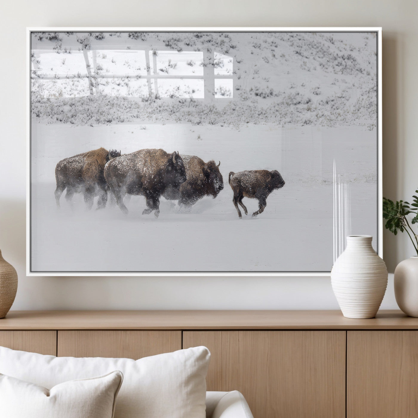 Bison herd running through a snowy open field with mountain backdrop, perfect for rustic or western-themed wall decoration.