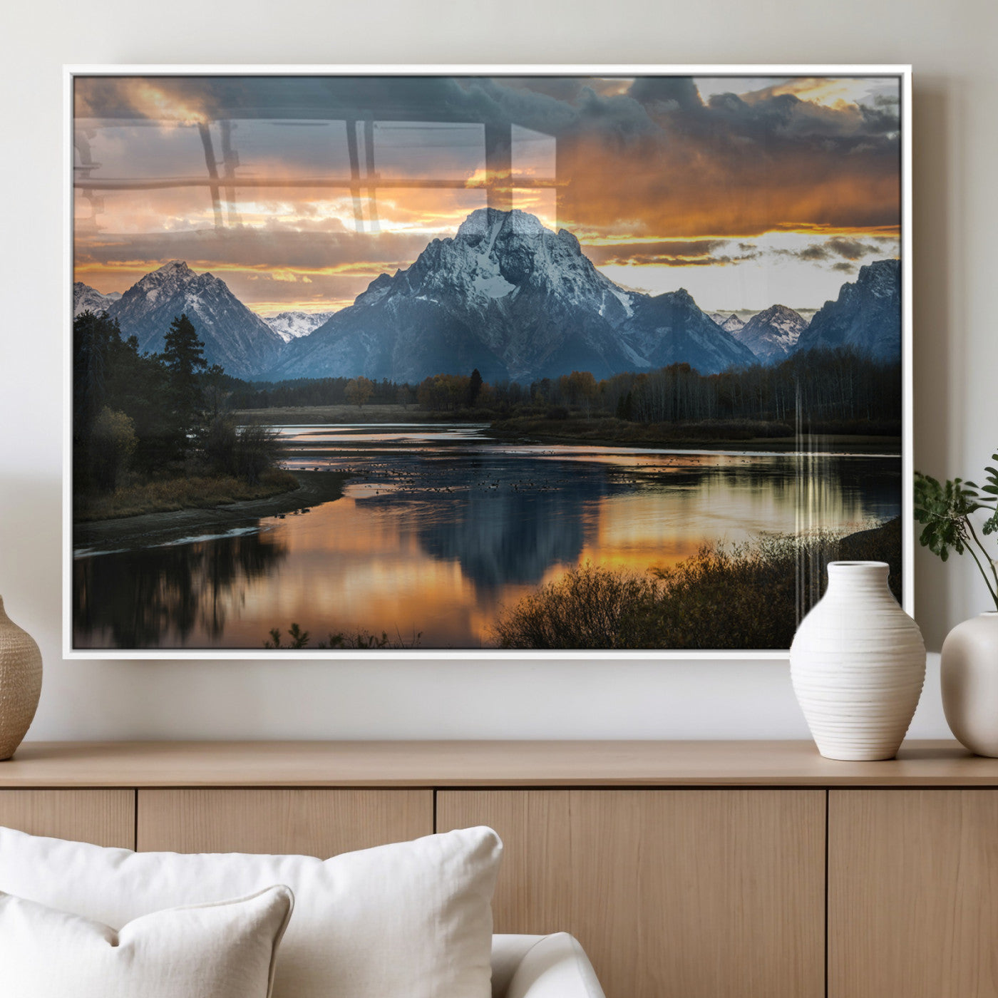 Snow-capped mountains reflecting in a calm lake at sunset, with a dramatic golden sky creating a breathtaking wilderness scene.