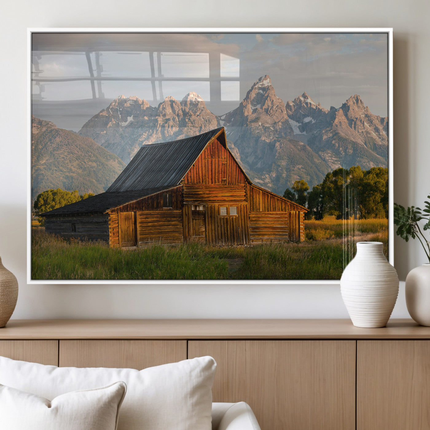 Rustic wooden barn set against towering mountain peaks under warm golden light, creating a peaceful Western countryside scene.
