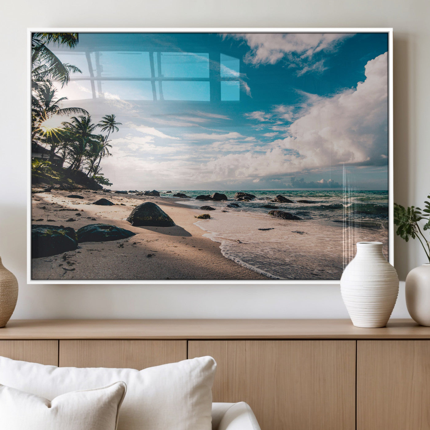 Scenic tropical beach with palm trees, ocean waves, and rocky shoreline under a bright blue sky, creating a serene coastal vibe.