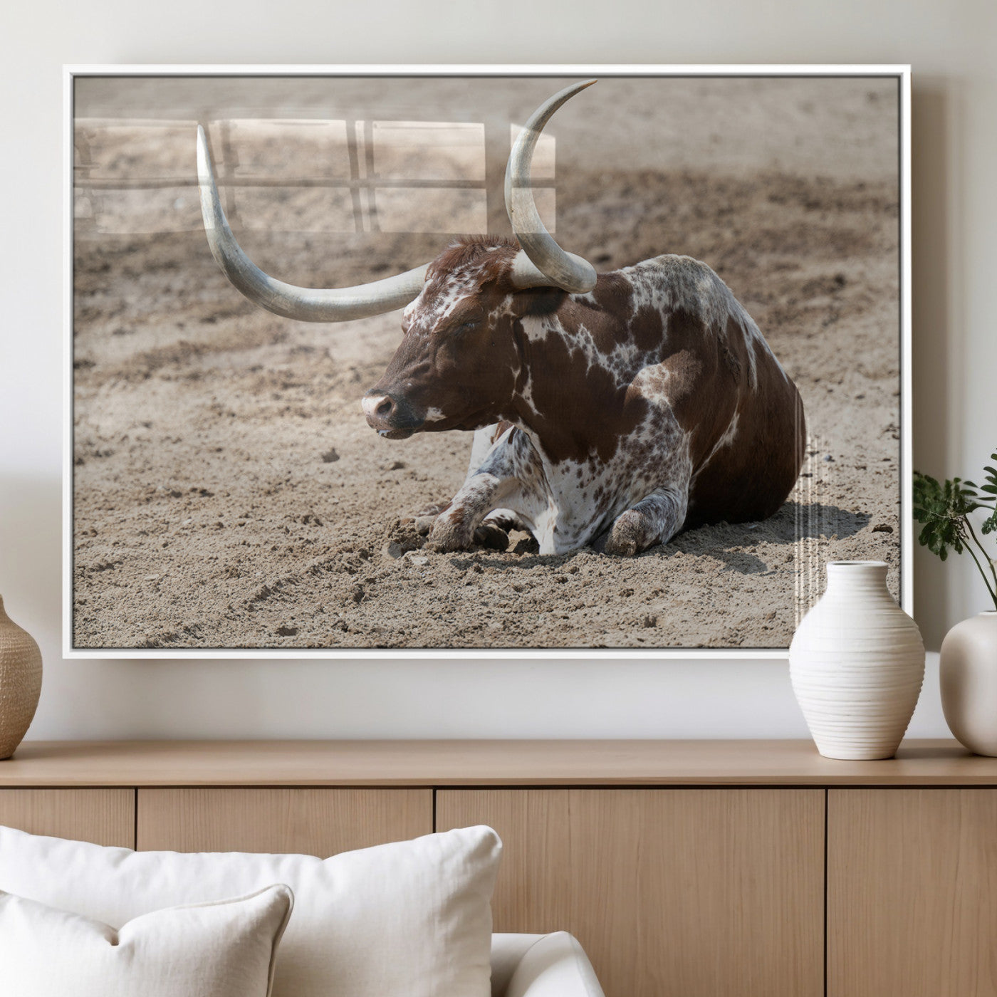 Texas Longhorn resting on sandy ground with large curved horns, capturing a rustic Western aesthetic perfect for farmhouse-style wall art.
