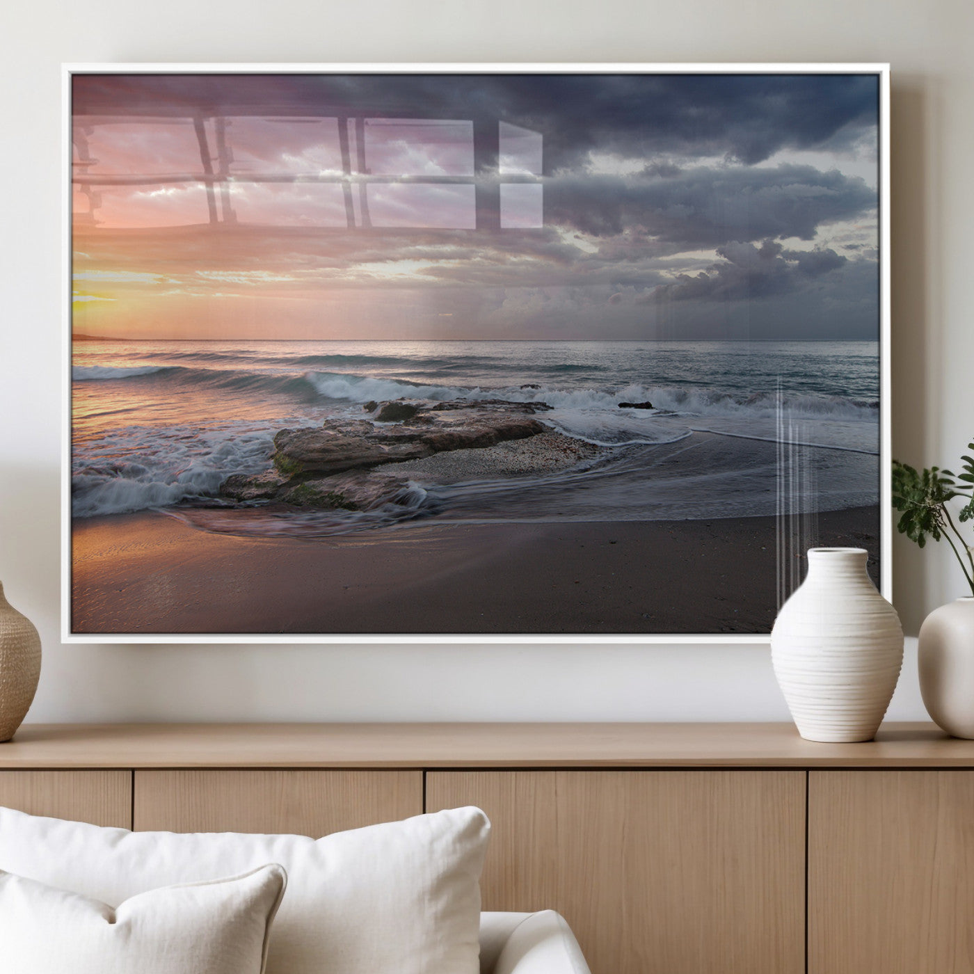 Dramatic sunset over a rocky shoreline with ocean waves gently reaching the sandy beach, creating a serene and coastal atmosphere.