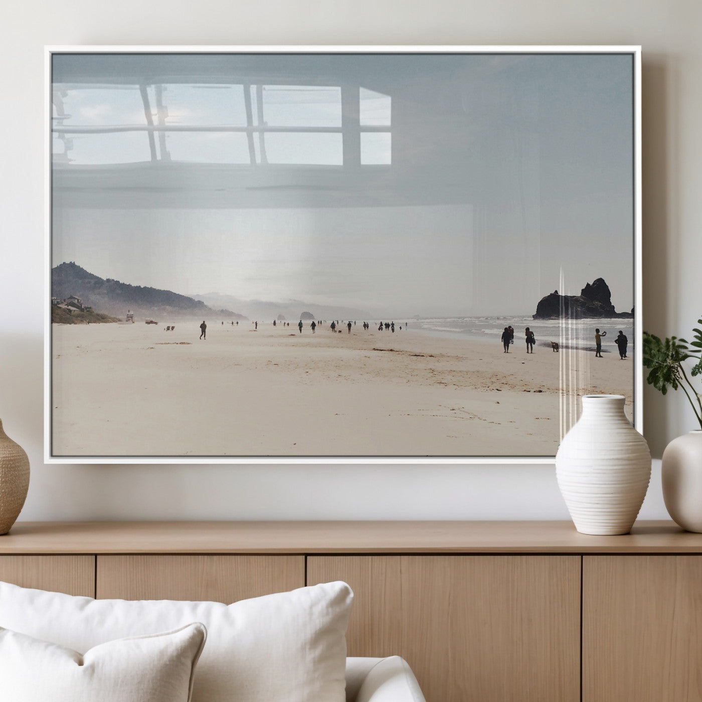 A serene beach with soft sand, misty mountains, and scattered people walking along the shoreline, creating a peaceful coastal landscape.