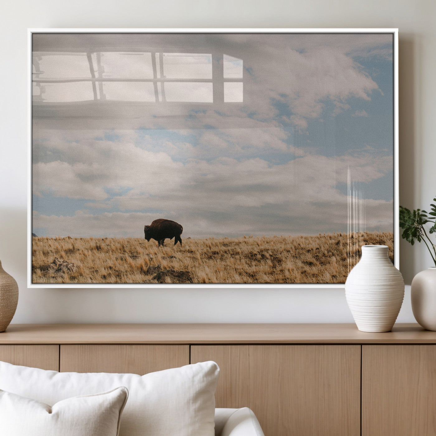 A solitary bison walking across a golden prairie under a vast, cloud-filled sky, evoking a peaceful, rustic western landscape for home decor.