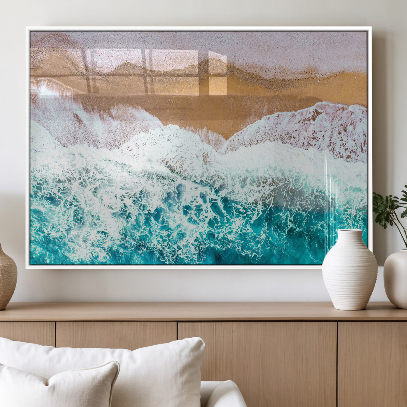 Aerial view of ocean waves crashing onto a sandy beach, with turquoise water and foamy white surf, creating a serene coastal aesthetic for home decor.