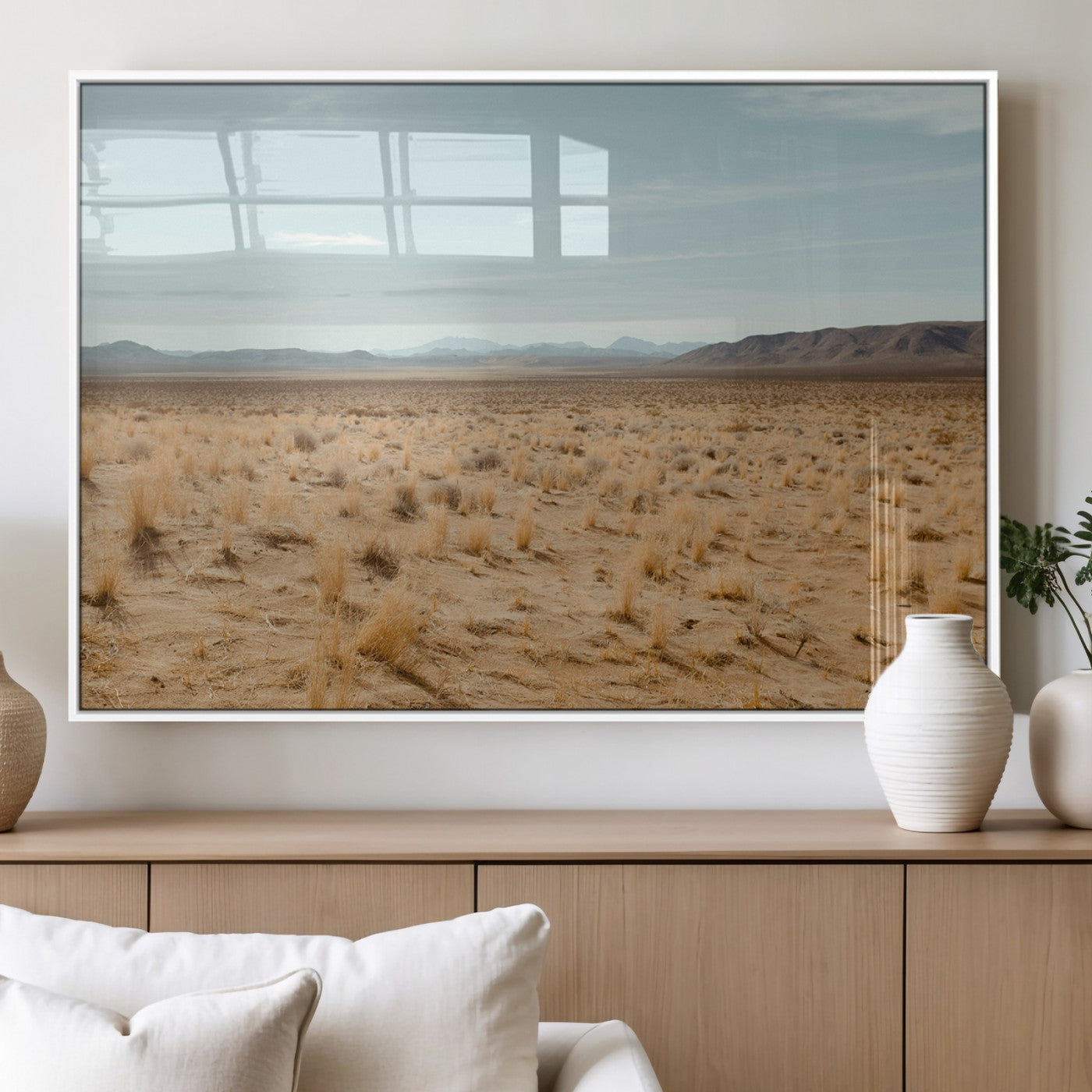 Expansive desert landscape with scattered dry grass and distant mountain range under a pale blue sky – Wall Art Canvas Print.