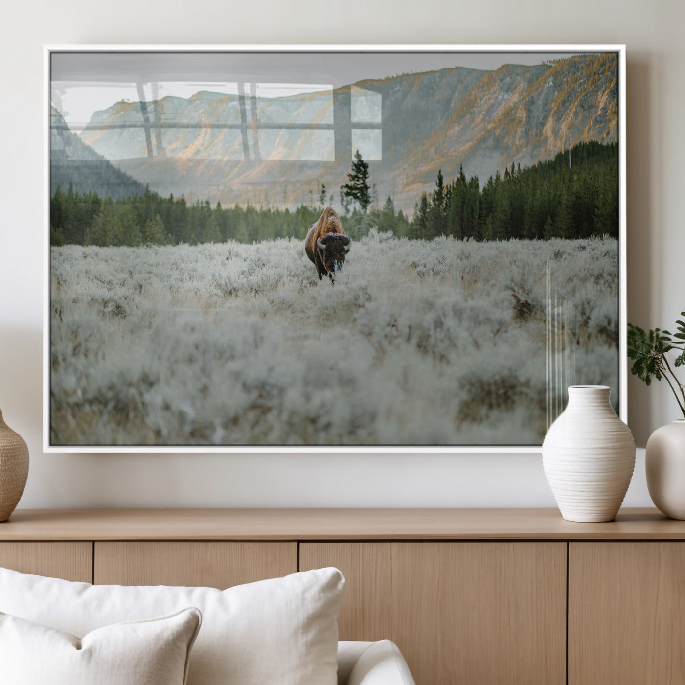 Lone bison standing in a frosted sagebrush field with a pine forest and rugged mountain range in the background under soft morning light – Wall Art Canvas Print.