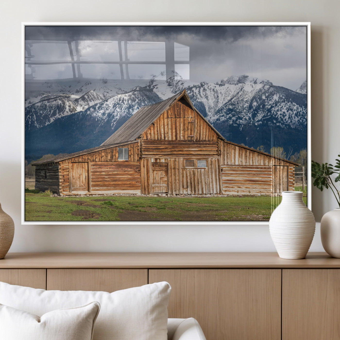 A stunning wall art canvas print featuring a rustic wooden barn set against a backdrop of snow-capped mountains under a dramatic cloudy sky, perfect for adding a touch of rural charm to any space.