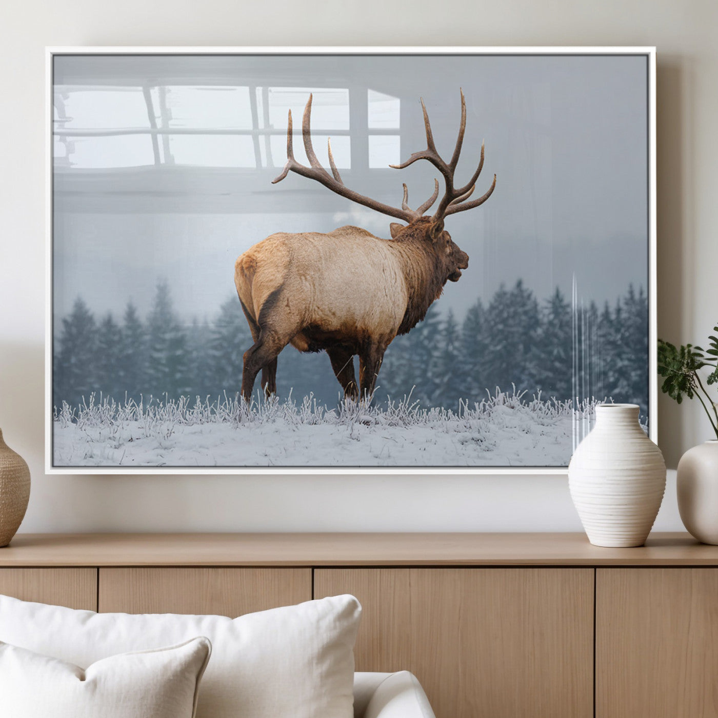 A majestic elk standing in a snowy landscape, with large antlers, set against a backdrop of evergreen trees and a soft winter sky.