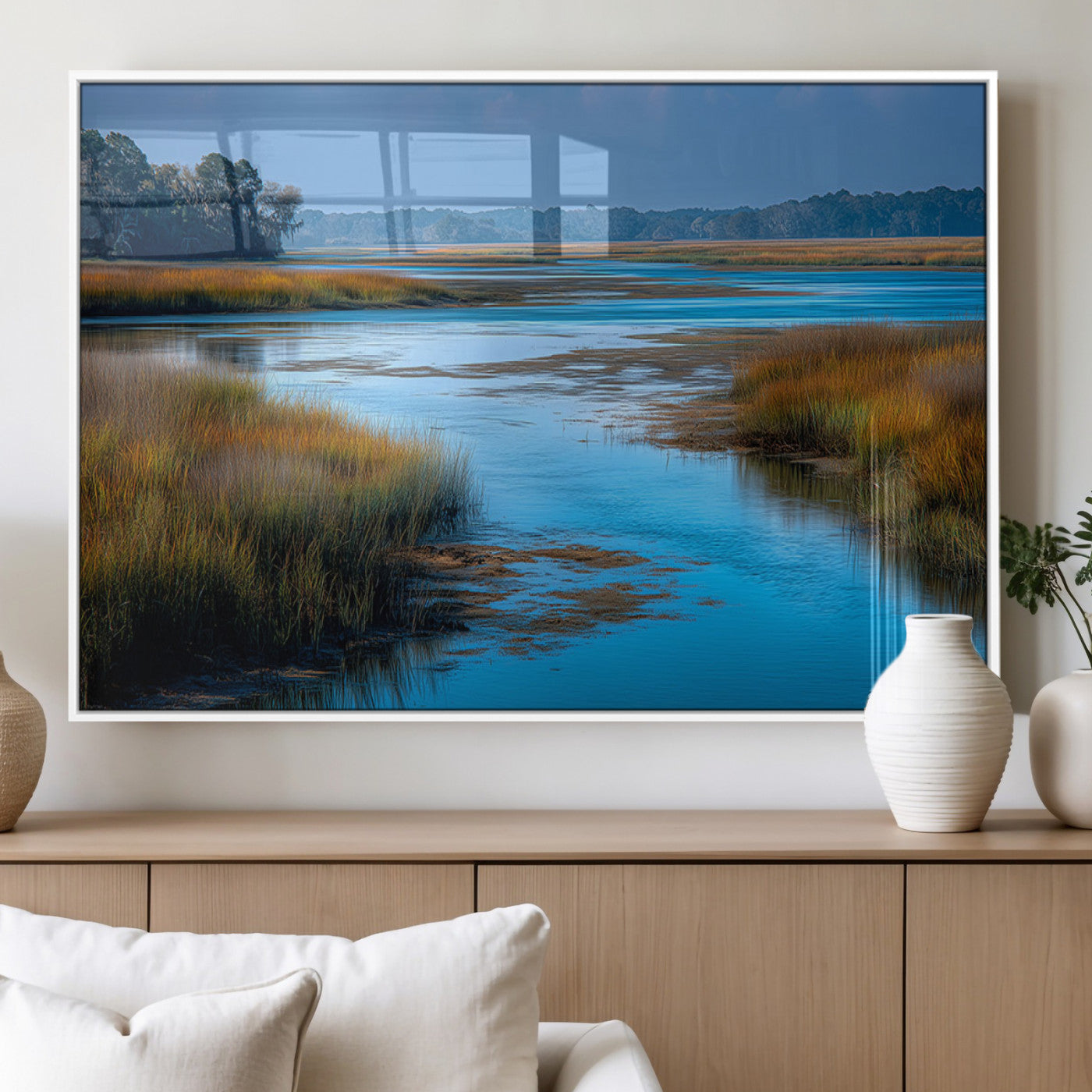 A peaceful marshland scene with calm blue water reflecting the surrounding grasses and trees, capturing the beauty of nature in a serene landscape.