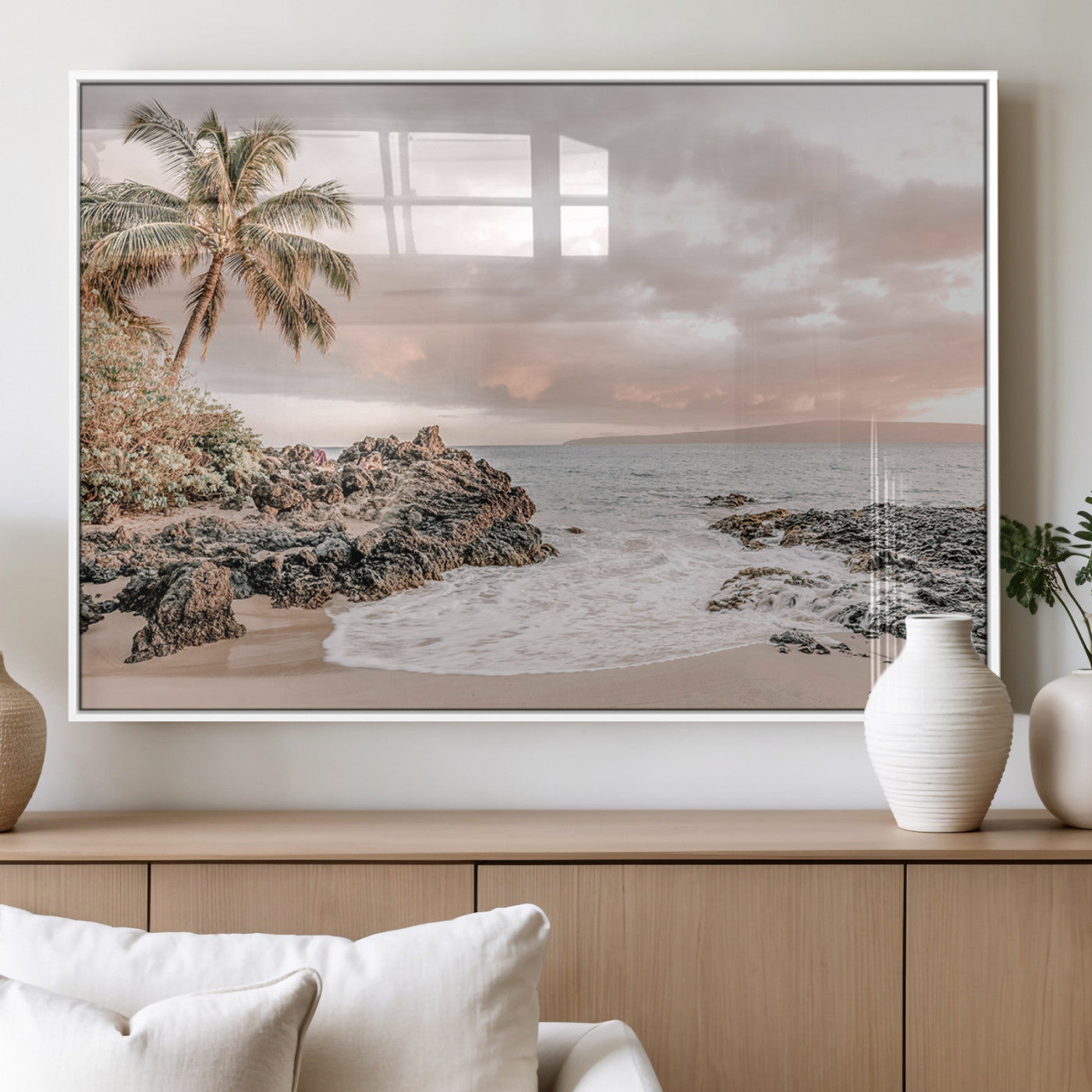 A peaceful beach scene with a palm tree and rocks, soft waves washing onto the shore under a soft pastel sky at sunset.