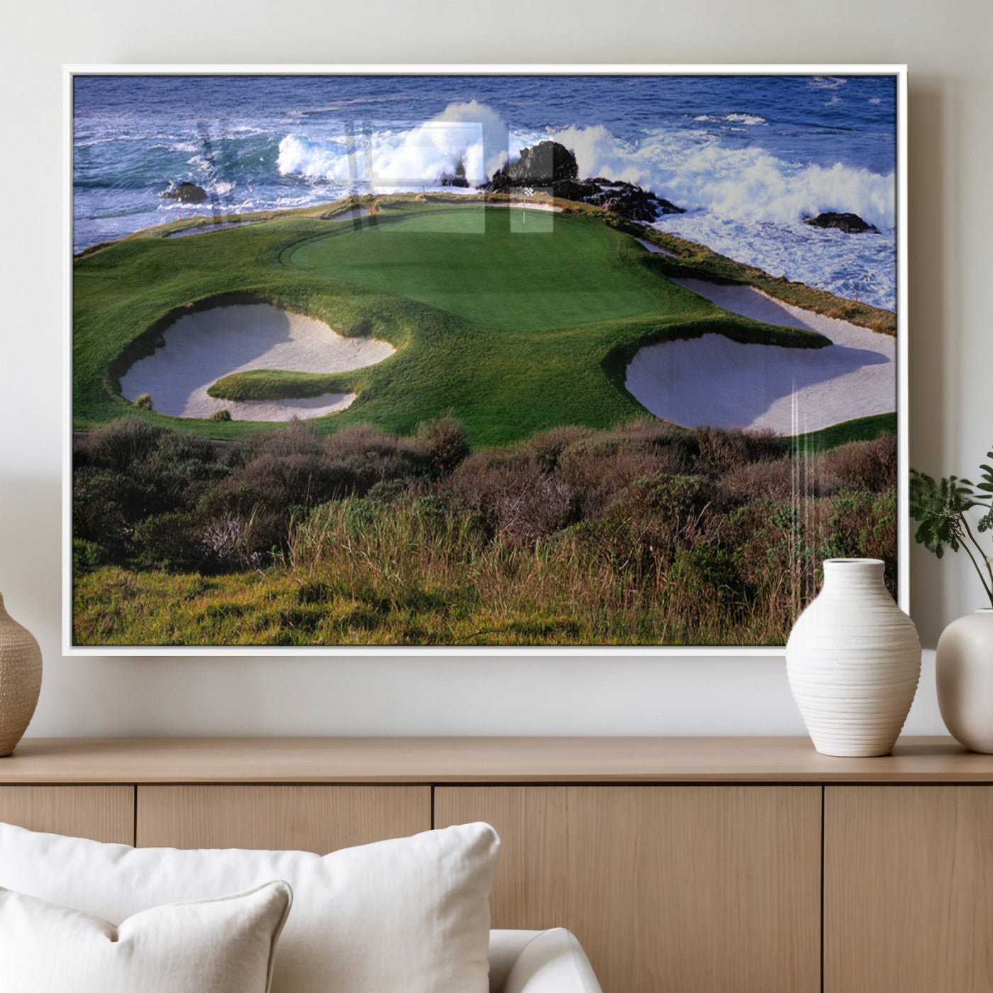 A scenic golf course located by the ocean, featuring a well-manicured green surrounded by sand traps and powerful ocean waves crashing on the shore.