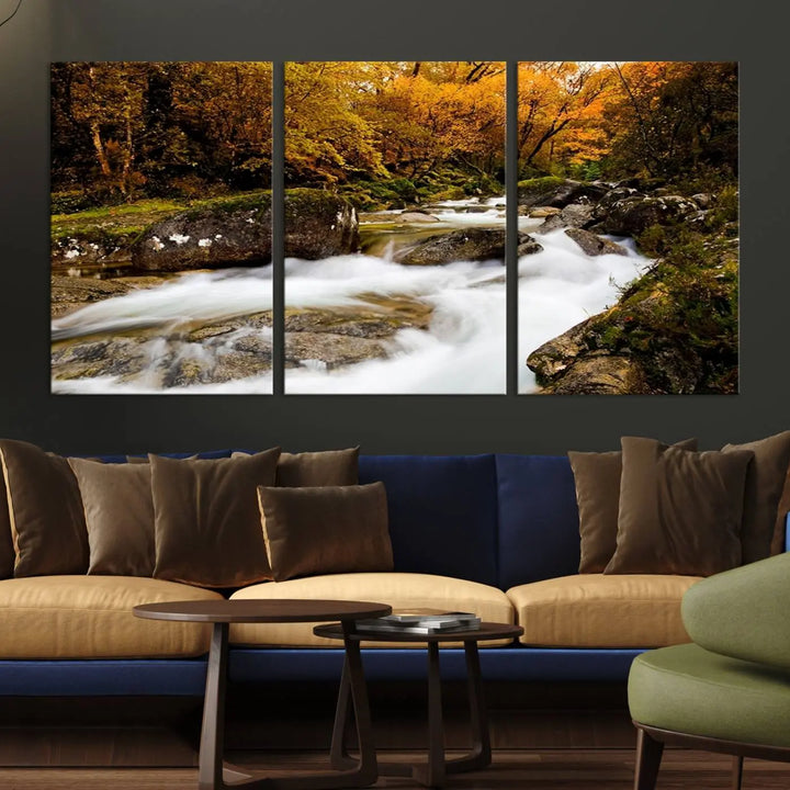 The living room is adorned with the "Wall Art Waterfall Canvas Print River in Forest in Autumn," a triptych on museum-quality canvas showcasing a flowing river surrounded by autumn trees. This ready-to-hang artwork features a UV-protective coating to ensure enduring vibrancy.