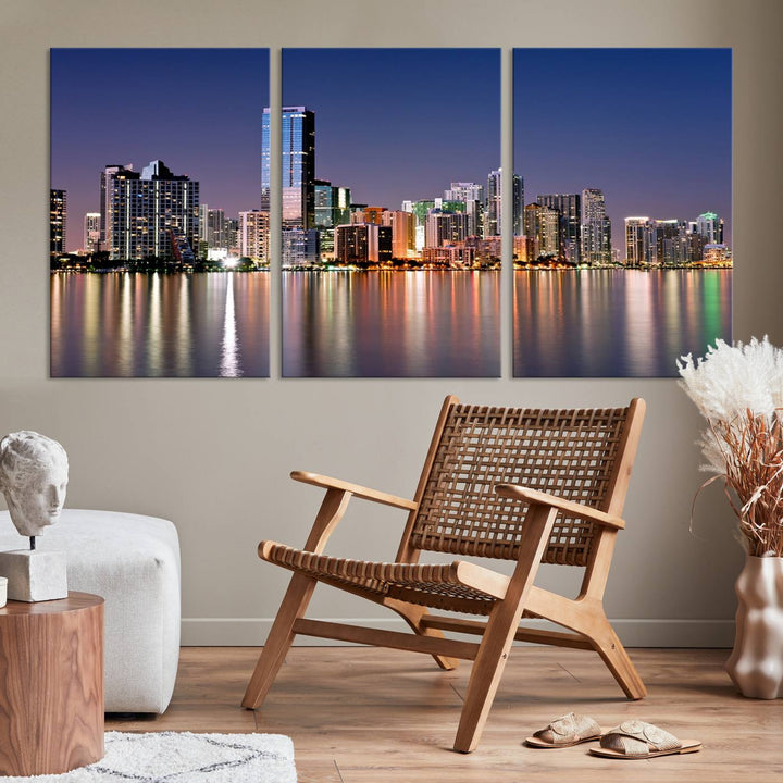 The Miami Skyline Canvas Wall Art Print showcases a vibrant night cityscape and beautifully captures the dazzling colorful lights reflecting on the water. This ready-to-hang triptych adorns the wall, creating a stunning visual centerpiece.